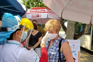 Nhân viên y tế đo thân nhiệt cho một du khách nước ngoài tại điểm chốt ra vào thành phố Đà Nẵng. Ảnh: T.AN 