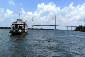 Những chuyến phà của Cụm phà Vàm Cống vẫn miệt mài qua lại đôi bờ, còn phía xa cầu Vàm Cống đã hoàn tất chờ ngày thông xe. Ảnh HOÀNG THỊ)