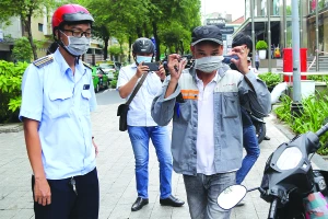 Lực lượng trật tự đô thị phường Bến Nghé (quận 1, TP.HCM) nhắc nhở và phát khẩu trang cho một người dân khi người này không đeo khẩu trang ra đường. Ảnh: HOÀNG GIANG