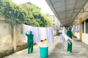 Các hộ lý gom quần áo, ga giường, gối mền, khăn mặt của người cách ly mang đi giặt mỗi ngày. Ảnh: HOÀNG LAN