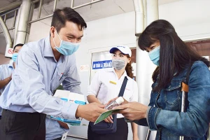 Ông Lê Hoàng, Phó Giám đốc Trung tâm Quản lý giao thông công cộng, tặng khẩu trang và nước rửa tay cho hành khách đi xe buýt. Ảnh: NGUYỄN TRÀ