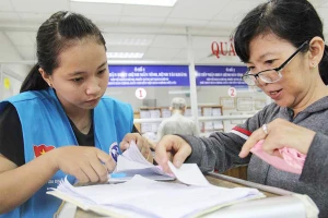 Tình nguyện viên hướng dẫn người bệnh làm thủ tục khám bằng BHYT ở BV Nhân dân Gia Định. Ảnh: HOÀNG GIANG