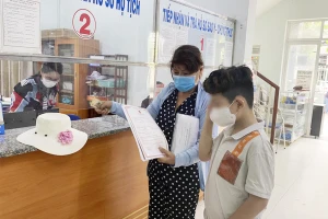 Tuấn cùng mẹ đến UBND phường 12, quận Bình Thạnh nhận giấy khai sinh sau nhiều năm chờ đợi. Ảnh: HỮU ĐĂNG