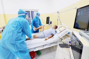 Kỹ thuật viên tại BV 1A hỗ trợ bệnh nhân COVID-19 tập vận động. (Ảnh bệnh viện cung cấp)