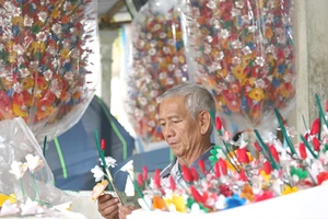 Ông Nguyễn Hóa đang tỉ mỉ làm ra những bông hoa giấy. Ảnh: N.DO