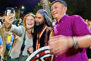 Du khách chụp ảnh lưu niệm cùng các nghệ nhân. Ảnh: LÊ KIẾN