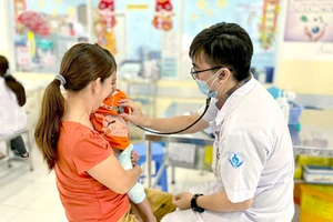 Bác sĩ Lý Hiển Khánh thăm khám cho bệnh nhi tại khoa Nhiễm - Thần kinh BV Nhi đồng 1. Ảnh: THẢO PHƯƠNG