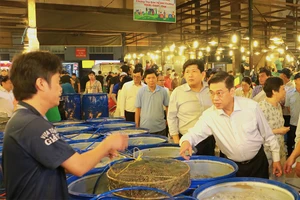 Phó Chủ tịch UBND TP.HCM Nguyễn Văn Dũng trao đổi với tiểu thương tại chợ Bình Điền khuya 25-1. Ảnh: VÕ THƠ