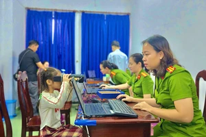 Công an phường Thủ Đức hỗ trợ em bé bước "quét móng mắt" để làm CCCD. Ảnh: PHẠM HẢI