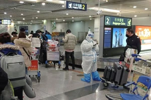 Hành khách của các chuyến bay quốc tế xếp hàng chờ nhân viên mặc đồ bảo hộ cá nhân (PPE) tại sân bay tỉnh Thành Đô, Trung Quốc ngày 1-8 Ảnh: AFP