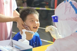 Nhân viên y tế lấy mẫu xét nghiệm COVID-19 tại một điểm xét nghiệm ở TP Trịnh Châu, tỉnh Hà Nam ngày 8-1. Ảnh: REUTERS