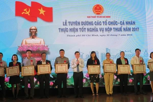 Ông Nguyễn Thành Phong, Chủ tịch UBND TP.HCM (áo trắng, giữa) trao bằng khen cho các doanh nghiệp hoàn thành tốt nghĩa vụ nộp thuế năm 2017- Ảnh: QH