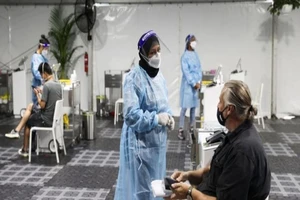 Nhân viên y tế Úc xét nghiệm cho du khách tại sân bay Sydney. Ảnh: REUTERS