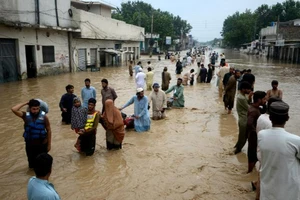 Người di dời lội qua một khu vực ngập nước ở thành phố Peshawar, tỉnh Khyber Pakhtunkhwa (Pakistan) ngày 27-7. Ảnh: CNN