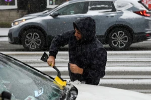Một cư dân bang Illinois (Mỹ) cạo tuyết trên xe ô tô ngày 22-12. Ảnh: REUTERS