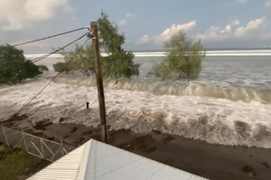 Sóng ập vào các ngôi nhà ven biển tại đảo Tonga. Ảnh: EFE