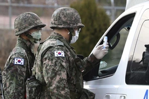 Binh sĩ Hàn Quốc kiểm tra thân nhiệt một tài xế ở chốt kiểm soát một căn cứ quân sự ở Daegu (Hàn Quốc). Ảnh: AP