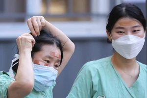 Nhân viên y tế dùng băng dính che vết thương do khẩu trang gây ra. Ảnh: YONHAP