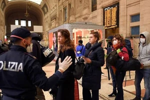 Cảnh sát trao đổi với người dân tại ga tàu lửa chính ở Milan, vùng Lombardy (Ý) ngày 9-3. Ảnh: REUTERS