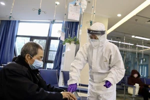 Giúp một người nhiễm COVID-19 được điều trị hồi phục xuất viện ở tỉnh Hồ Bắc ngày 7-3. Ảnh: THX