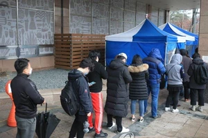 Nhân viên làm trong tòa nhà có người nhiễm COVID-19 ở Seoul phải xếp hàng chờ kiểm tra nhiệt độ trước khi vào làm việc ngày 10-3. Ảnh: YONHAP