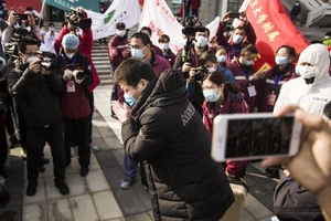 Một bệnh nhân hồi phục xuất viện ở Vũ Hán (Trung Quốc) chắp tay cám ơn các bác sĩ cứu chữa cho mình. Ảnh: SCMP