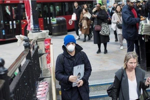 Một thanh niên mang khẩu trang xuống một trạm tàu điện ngầm ở London (Anh) ngày 13-3. Ảnh: REUTERS