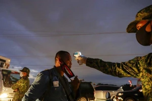 Cảnh sát kiểm tra nhiệt độ dân tại một chốt kiểm soát phong tỏa ở Manila (Philippines) ngày 16-3. Ảnh: AP