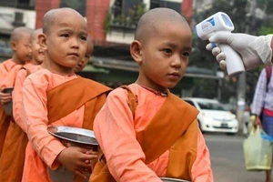 Các chú tiểu được kiểm tra nhiệt độ trên đường phố Yangon (Myanmar). Ảnh: AFP