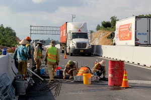 Ảnh: Công nhân làm việc giữa dòng xe cộ trên cao tốc Nha Trang - Cam Lâm