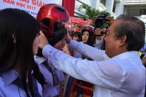 Phó Thủ tướng Trương Hòa Bình đội mũ bảo hiểm cho HS