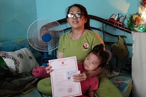 Bà Thủy vui mừng khi đứa cháu nội được cấp giấy khai sinh. Ảnh: NGUYỄN HIỀN