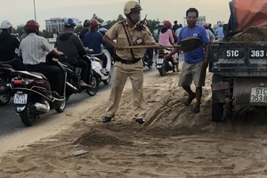  Cảnh sát vác xẻng dọn vệt cát 20 m trên cầu vượt Quang Trung