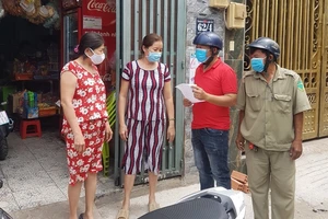 Cán bộ phường Bình Hưng Hòa A, quận Bình Tân, vận động người dân đeo khẩu trang. Ảnh: LÊ THOA 
