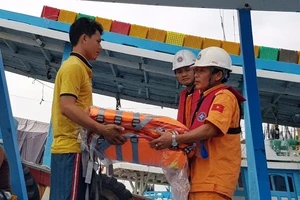 Tổ công tác của tàu SAR tặng áo phao cho ngư dân