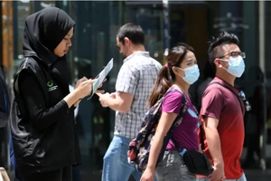 Một tình nguyện viên thuộc Bộ Truyền thông Singapore thu thập phản ánh của người dân về tình hình dịch COVID-19.