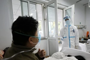 Một nhân viên y tế trong trang phục bảo hộ tương tác với một bệnh nhân trong khu cách ly tại bệnh viện Jinyintan ở Vũ Hán, Trung Quốc.