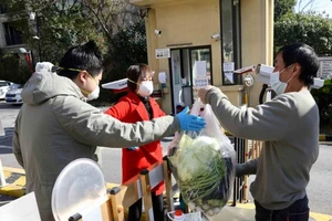 Người dân lấy rau họ mua tại cổng một khu dân cư ở Vũ Hán. 