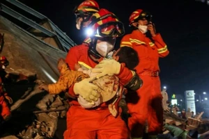 Lực lượng cứu hộ giải cứu một trẻ em mắc kẹt trong đống đổ nát của khách sạn Xinjia. Ảnh: AFP