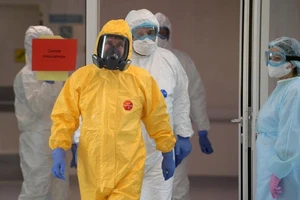 Tổng thống Putin mặc bộ đồ phòng dịch màu vàng, đeo găng tay xanh, mang ủng và đeo mặt nạ phòng độc kỹ càng vào bệnh viện thăm bệnh nhân COVID-19. Ảnh: RT