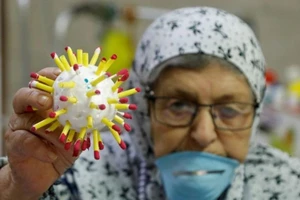 Một cụ bà tại nhà dưỡng lão Palestine cầm một mô hình virus Corona. Ảnh: REUTERS