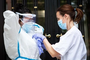 Một ý tá giúp đồng nghiệp mặc đồ bảo hộ cá nhân trước khi đi vào nhà một bệnh nhân COVID-19 ở Madrid, Tây Ban Nha. Ảnh: GETTY