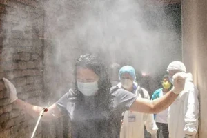 Một phụ nữ được xịt khử trùng ở Nepal. Ảnh: AFP