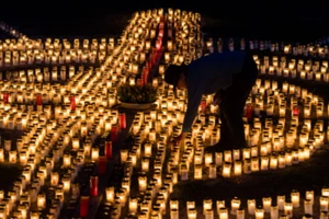 Một người dân thắp nến hình chữ thập cầu nguyện cho những người qua đời vì COVID-19 tại Đức. Ảnh: GETTY IMAGES