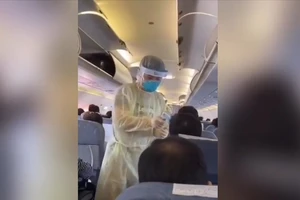 Nhân viên y tế đo nhiệt độ hành khách trước khi rời máy bay