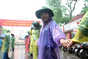 Tình nguyện viên đội mưa che chắn cho sĩ tử