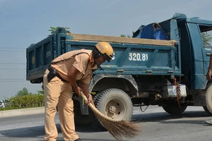 Cảnh sát giao thông đội nắng dọn đá rơi vãi trên đại lộ