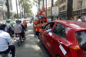 Bị cẩu xe, tài xế cố thủ ngồi hút thuốc trong cabin