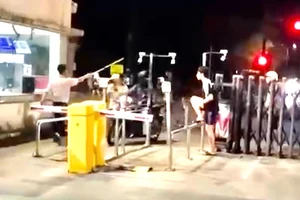 Người mang trang phục bảo vệ cầm gậy đánh nam thanh niên trước cổng ký túc xá làng đại học