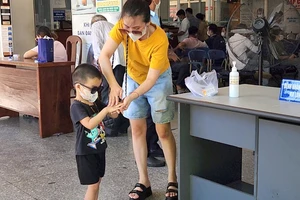 Hai mẹ con sát khuẩn tay bằng cồn khi đến khám đau mắt đỏ tại Bệnh viện Mắt Đà Nẵng.